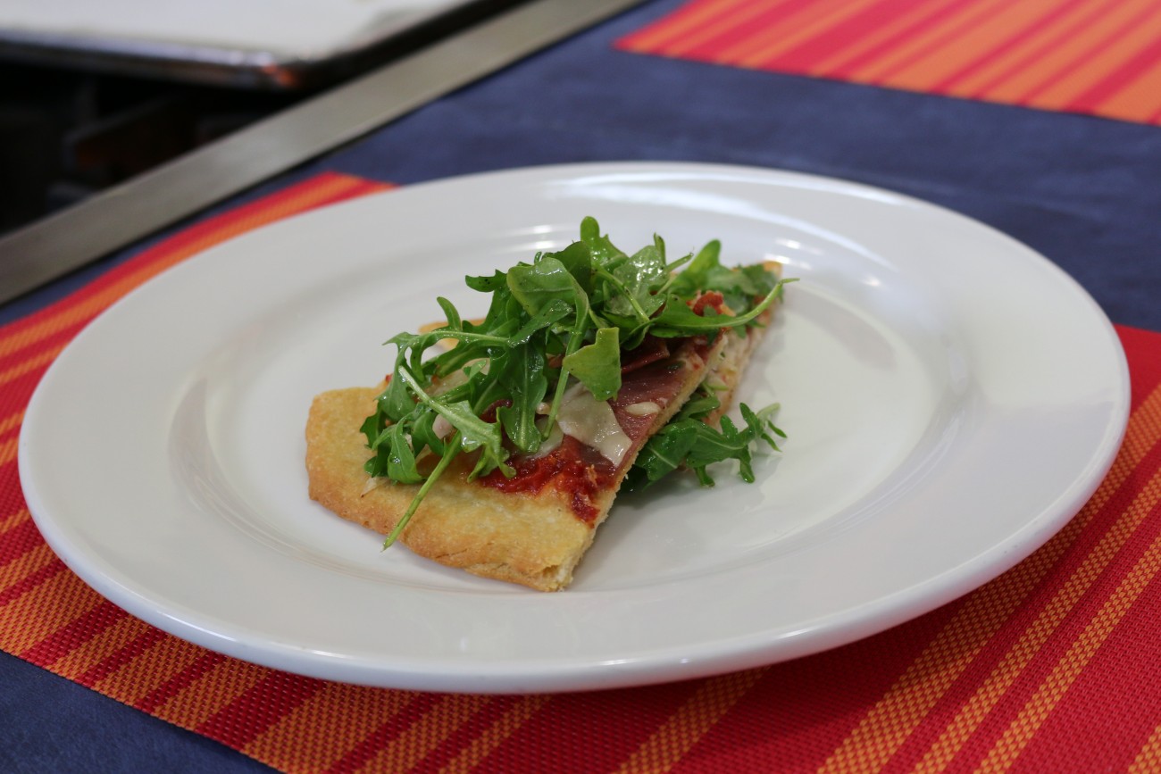 Pizza de prosciutto y ensalada de arúgula